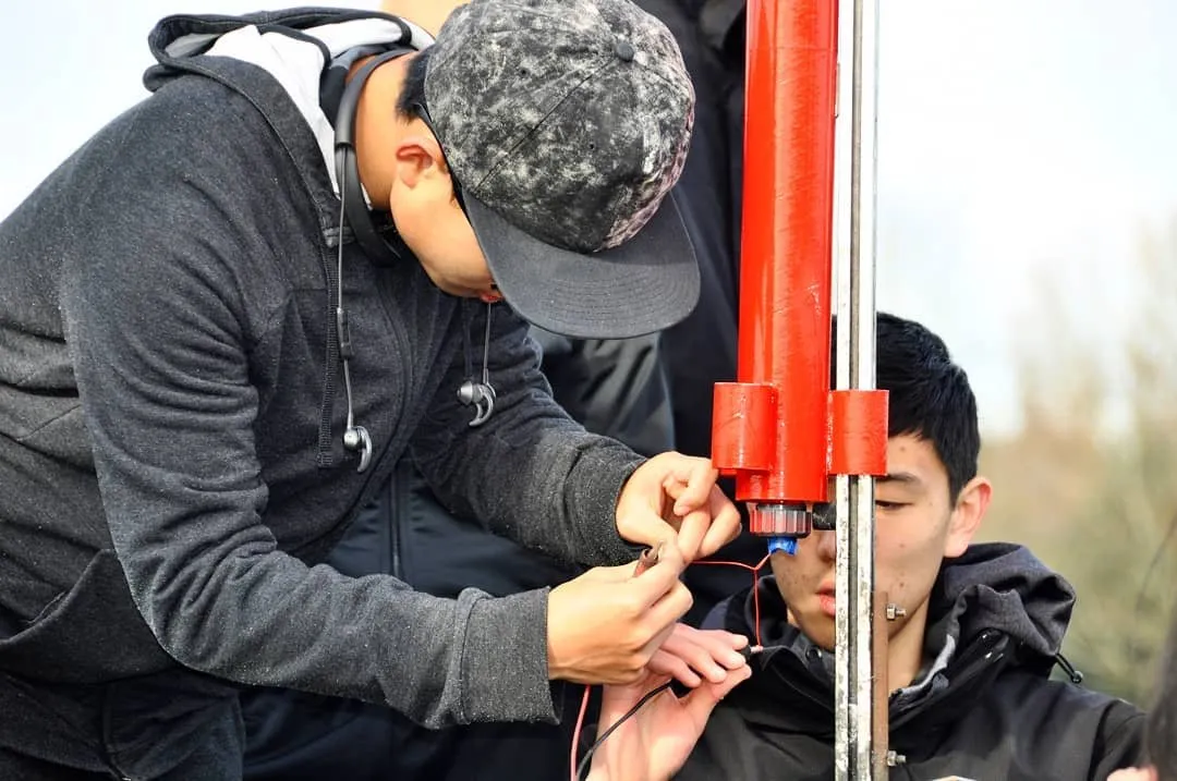 A team captain helping a new member prepare a red rocket